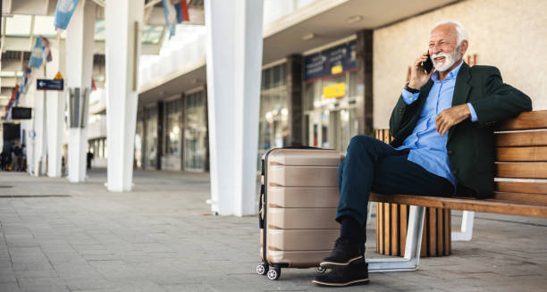 istock Senior man talking on smart phone while standing at train station. 2184174344