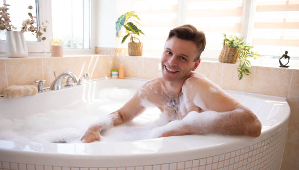 istock A smiling man enjoys a relaxing bubble bath in a bright, sunlit bathroom. Surrounded by plants and minimalistic decor, the scene conveys relaxation, comfort, and self-care in a cozy home setting. 2184175493