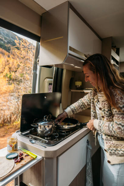 istock Woman Cooking Inside Cozy Camper Van in Autumn Forest 2184175570