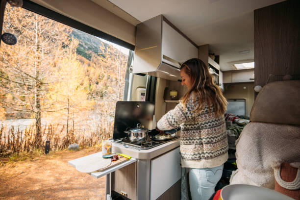 istock Woman Cooking Inside Cozy Camper Van in Autumn Forest 2184175646
