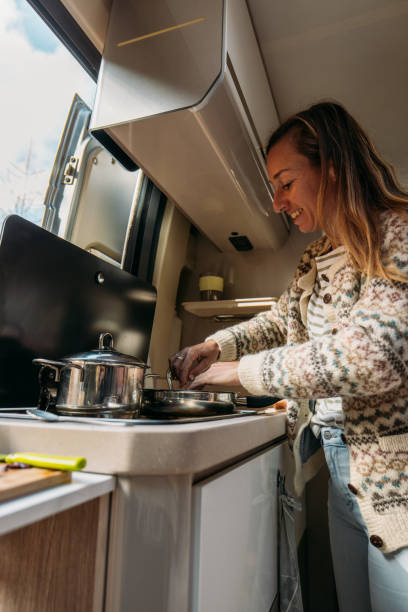 istock Woman Cooking Inside Cozy Camper Van in Autumn Forest 2184175651