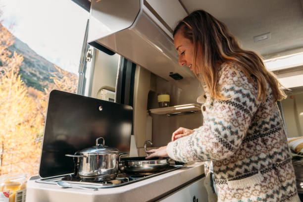 istock Woman Cooking Inside Cozy Camper Van in Autumn Forest 2184175860