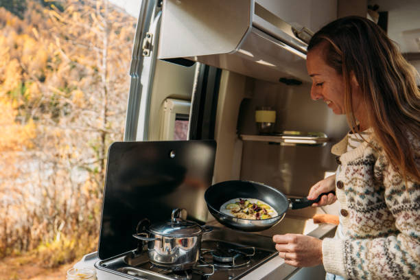 istock Woman Cooking Inside Cozy Camper Van in Autumn Forest 2184176042