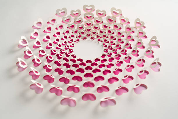 Native image size: 7952 x 5304. Close-up of a spiral paper artwork featuring layered heart cutouts in shades of pink and white. The intricate design forms a charming, romantic pattern, perfect for Valentine’s Day themes or love-inspired decor.