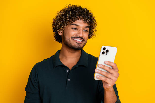 istock Young man checking smartphone against vibrant yellow background showing happy expression 2184176436