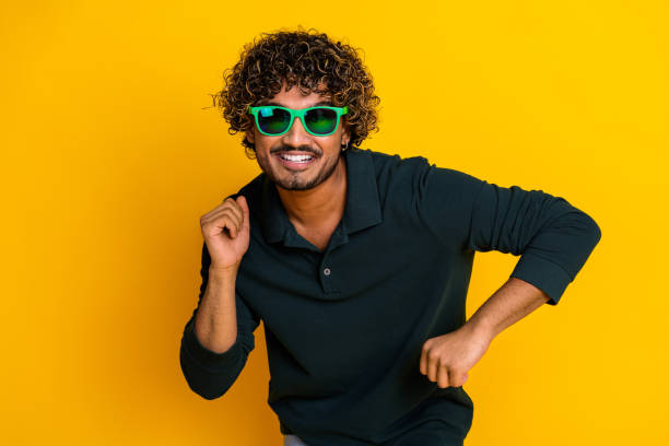 istock Young man dancing joyfully against a vibrant yellow background, expressing happiness and fun exudes positive energy and excitement. 2184176621