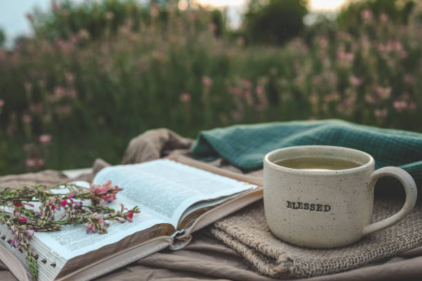 Cup with text BLESSED and open Bible in the garden, good morning