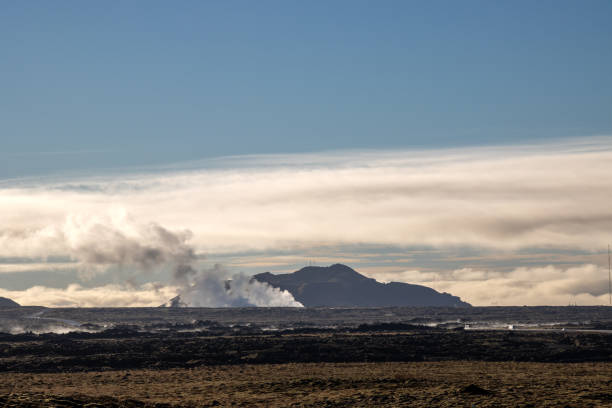 Volcanic field covered by moss and lichen. Mountains and a steam from geothermal sources. Blue sky with clouds in the autumn. Grindavik, Iceland.