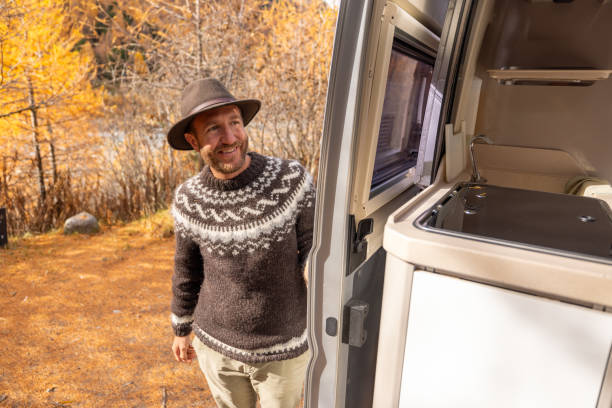 istock Smiling Man in Sweater by Camper Van in Autumn Setting 2184179139