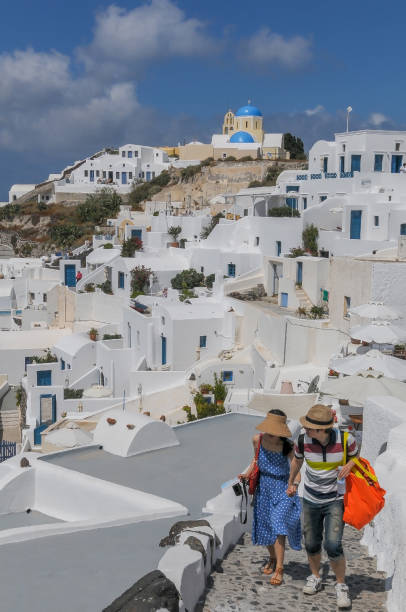 Santorini, Greece. October 4th, 2023: Tourists In Oía with the typically blue dome and church bells, Santorini