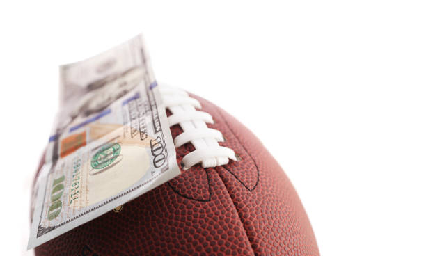 istock Hundred dollar bill on a football, isolated on white 2184183724
