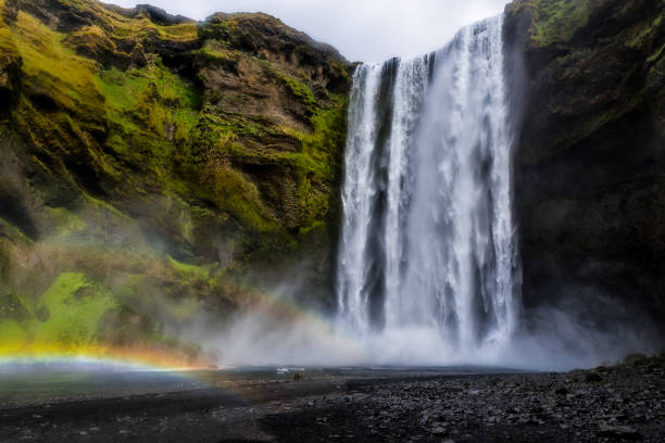 Breathtaking view of a powerful Gullfoss waterfall in Iceland, where sunlight creates a vibrant rainbow above the cascading water.