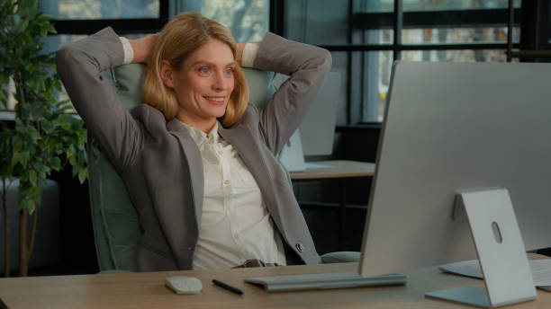 istock Smiling calm relaxed resting business woman finished computer work stretching sitting at desk in office. Happy middle-aged businesswoman satisfied after online complete job putting hands behind head 2184188715