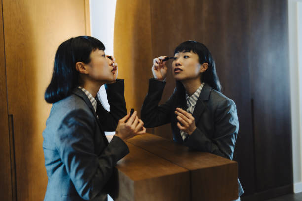 istock Businesswoman putting mascara, while observing herself in the mirror 2184189353
