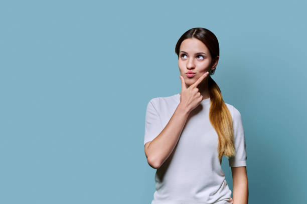 istock Young thoughtful teenage woman looking away at empty space for text image, on blue background 2184194921