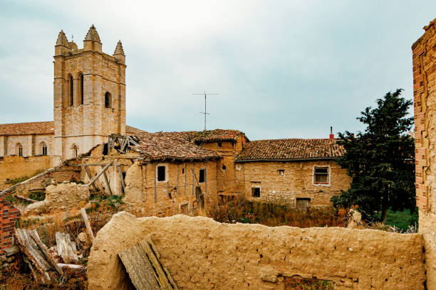 An ancient church tower and surrounding ruins in Castrojeriz, Spain. Captures the charm of Spanish heritage with rustic, timeworn architecture in a rural setting