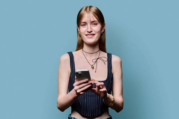 istock Young beautiful woman using smartphone on blue studio background 2184196098