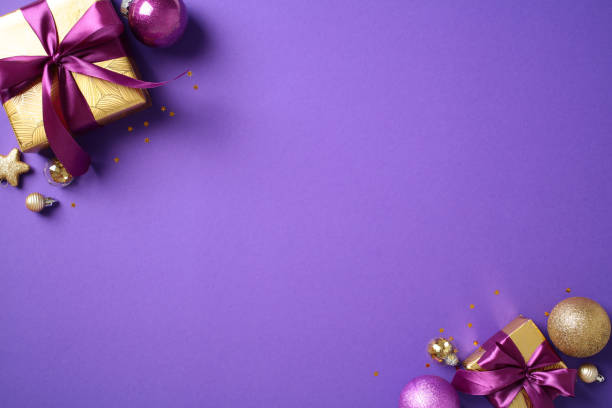 istock Christmas decorations with gold gift boxes and ornaments on purple background. Ideal for holiday-themed content, Christmas promotions, and seasonal marketing materials 2184197597