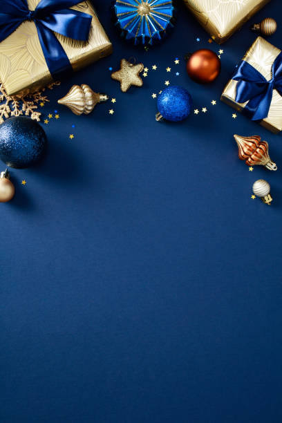 istock Elegant Christmas gold gift boxes with blue bows, festive decorations and baubles on chic blue background. Christmas poster design, party invitation template 2184198042