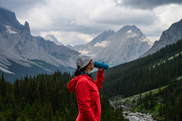 Woman drinks from water bottle in mountains