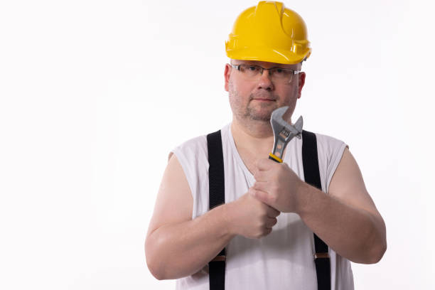 A construction worker in a yellow hard hat poses with a heavy wrench, ready for the work challenges ahead