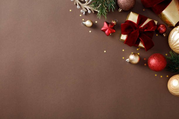 istock Stylish Christmas decorations on a brown background, featuring gold gift boxes, baubles, ornaments, star confetti, pine branches. Flat lay, top view, copy space. 2184198695