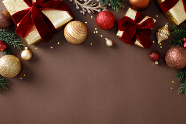 istock Elegant Christmas decorations on a brown background with gift boxes, ornaments, pine branches, and star confetti. Flat lay, top view, copy space 2184199064