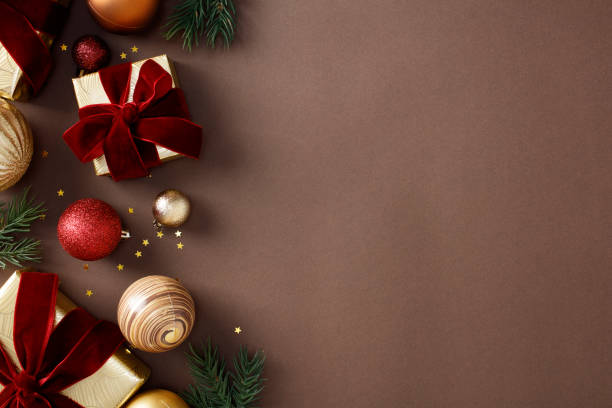 istock Christmas or winter holidays background with red and gold ornaments, gift boxes, pine branches, and stars on a brown background. Flat lay, top view, copy space 2184199088