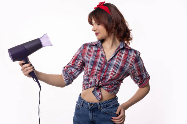 istock A Young Woman Playfully Using a Hair Dryer in a Retro and Stylish Way Within a Studio Setting 2184199703