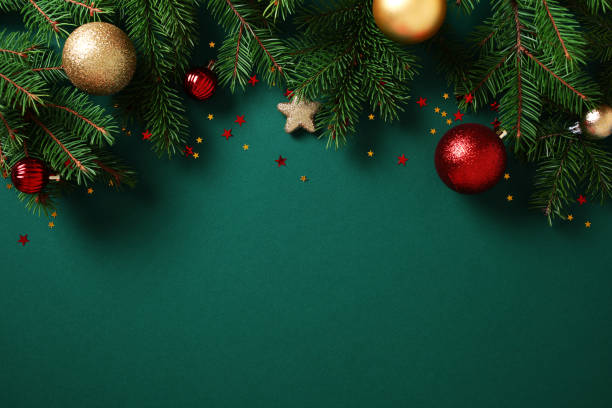 istock Christmas background. Green fir branches with gold and red baubles, stars, and confetti on a dark green backdrop. Christmas, winter holidays, New Year greeting card template 2184199708