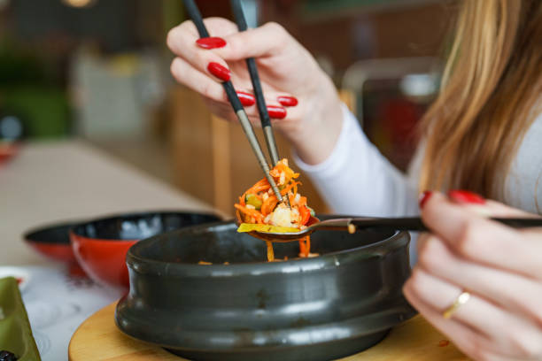 Young woman eating bibimbap at a Korean Restaurant.