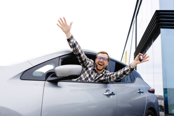 istock Excited young man showing a car key, sitting inside his new vehicle 2184205855