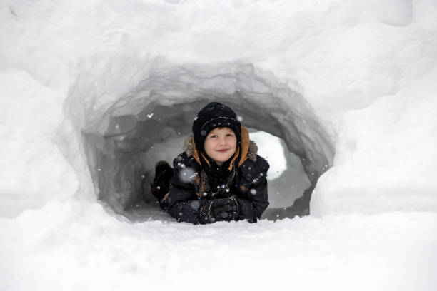 Young boy hiding in a snow cave he made