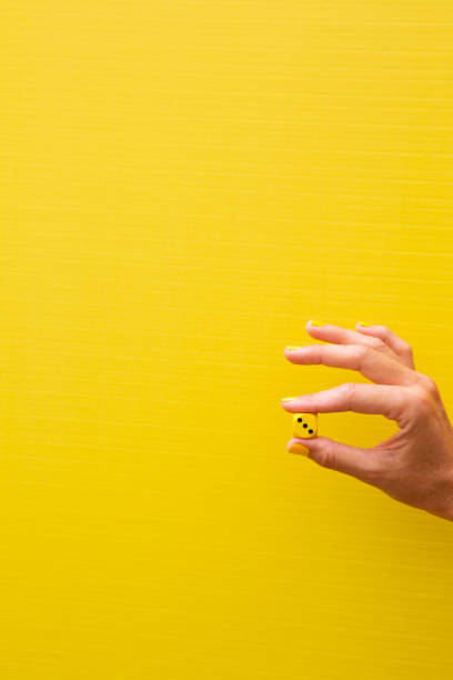 istock Woman's hand holding a yellow die with the number three on it 2184208069
