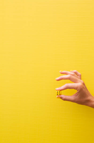 istock Woman's hand holding a yellow die with the number four on it 2184208074