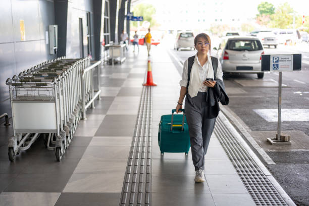 istock An Asian business woman pulling suitcase in airport terminal by using smartphone 2184209031