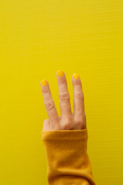 istock Three fingers of a woman's hand with yellow painted fingernails 2184210004