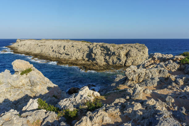 istock Rocky coastal landscape with serene waters under a clear sky at sunset. 2184213243