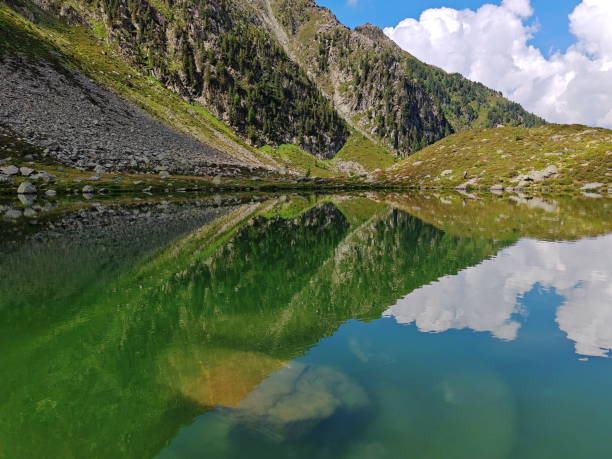 istock Tranquil  the Lago Chiusetta mountain lake (the Klaussee lake) reflecting green hills and clouds under a clear blue sky 2184214865