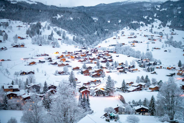 Grindelwald, under the soft glow of the night lights, transforms into a magical village where the snow glistens and each chalet seems to watch over the peaceful, slumbering mountains, Switzerland.