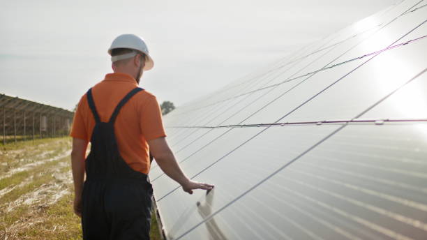 istock Professional male engineer in protective helmet walk on ecological solar plant construction. Concept of electricity, ecology, technologies. Farm of solar panels. Clean energy production. Green energy 2184215655
