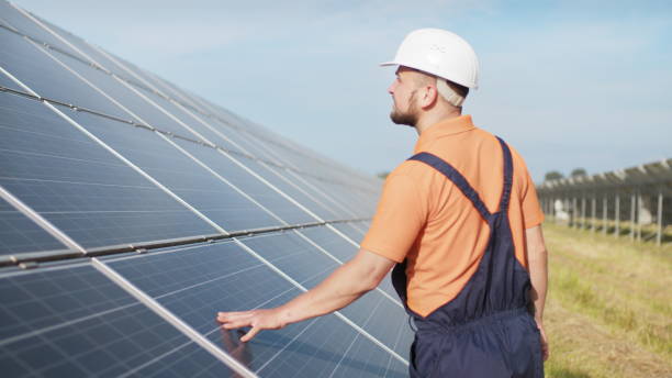istock Sustainable green energy jobs, solar panel technician working with solar panels. Assistance technical worker in uniform is checking an operation and efficiency performance of photovoltaic solar panels 2184215744