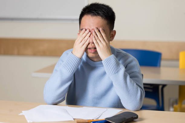 A student covering his eyes with his hands in stress