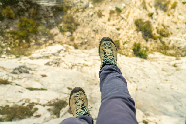One person, visible just waist down, on the newly built glass skywalk on Biokovo mountain. View down on Makarska Riviera and Adriatic sea on sunny day. Croatia.