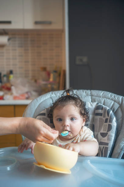 istock Baby Being Fed at Home in High Chair 2184220729