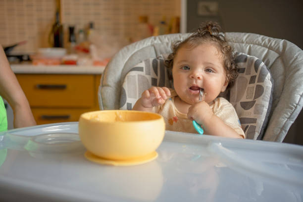 Playful Baby Holding Spoon During Mealtime