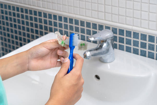 istock Hands cleaning dental retainer with toothbrush in bathroom 2184220821