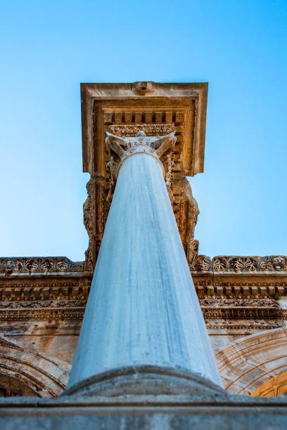 Partially preserved corinthian column rising against a clear blue sky at the Kourion archaeological site in Cyprus, a testament to ancient architecture