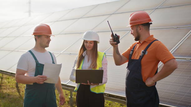 istock Three solar energy specialists walking at a solar power facility. Professional engineers discuss innovative project. Business team. Clean energy. Professional engineers discuss innovative project 2184225209