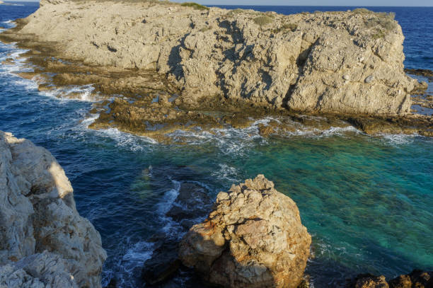 istock Exploring rugged coastal cliffs with turquoise waters beneath a bright sky at sunset. 2184225457